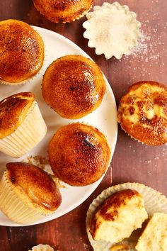 some muffins are on a plate with other muffins around them and sprinkled with powdered sugar