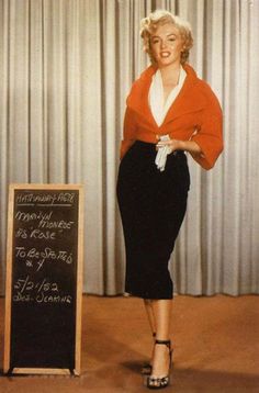 a woman standing in front of a chalkboard with writing on it and wearing heels