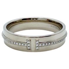 Tiffany & Co. T Collection Diamond Band Ring Style: Band Ref. number: 60150916 Metal: 18kt White Gold Rhodium Plated for Brilliance Size: 9.75 Measurements: 5.5 MM Main Diamond: 76 Round Brilliant Diamond 0.12 tcw Color & Clarity: White & Clean Hallmark: ©TIFFANY&Co. Au750 BELGIUM Includes: T&C Ring Pouch Est. Retail: $4,650.00 Sku#13138TBB04302024 Timeless Hallmarked Platinum Diamond Ring, Luxury Bands With Diamond Accents, Timeless Platinum Hallmarked Diamond Ring, Modern 14k White Gold Diamond Ring For Formal Occasions, Designer White Gold Diamond Ring With Single Cut Diamonds, Contemporary Hallmarked Rings For Formal Occasions, Designer Platinum Rings For Formal Occasions, Designer White Gold Rings For Formal Events, Luxury Platinum Diamond Ring Hallmarked