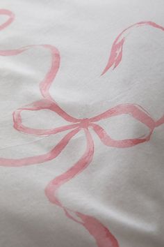 the pink ribbon is on top of the white bed sheet with it's design