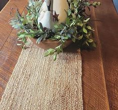 a wooden table topped with a vase filled with flowers and candles on top of it