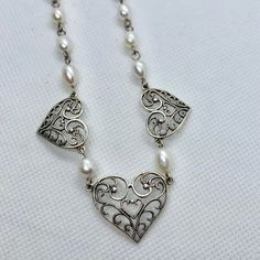 This Vintage Sterling Silver Heart and Pearl Necklace is beautiful. It's in very good condition it's adjustable it has 3 Hearts with the Center Heart being the largest and 1 Heart on either side. Very delicate and ornate design for the silver Hearts and beautiful pearls Great as Bridal Jewelry Heart Pendant Jewelry With Intricate Design For Wedding, Ornate Heart Pendant Necklace For Anniversary, White Heart Beaded Necklace For Wedding, Heart Cut Jewelry With Heart Beads For Wedding, White Heart Beads Necklace For Wedding, Silver Double Heart Wedding Necklace, Ornate Heart Charm Necklace, Silver Double Heart Necklace For Wedding, Silver Heart Necklace For Wedding