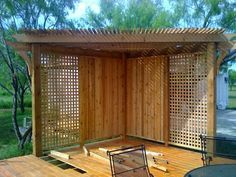 a wooden deck with a chair on it and a pergolated structure in the background