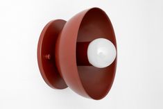 a red wall mounted light with a white ball on it