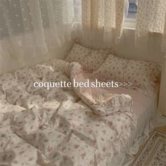 an unmade bed sitting in front of a window with the words coquette bed sheets on it