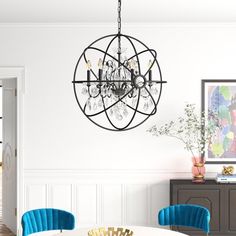 a chandelier hanging from the ceiling in a dining room with blue chairs and a white table