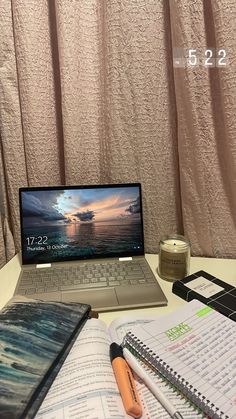 an open laptop computer sitting on top of a desk next to a notebook and pen