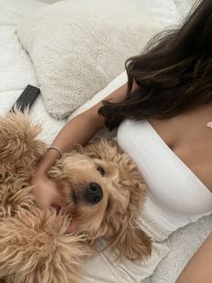 a woman laying in bed with her dog