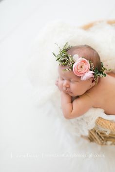 a newborn baby wearing a flower crown on her head