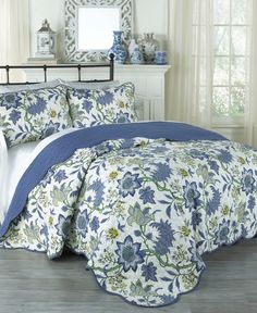 a bed with blue and white flowers on the comforter in front of a window