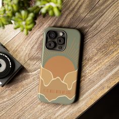 an iphone case sitting on top of a wooden table next to a camera and phone