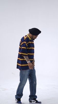 a young man riding a skateboard on top of snow covered ground in front of a white wall