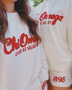 two people standing next to each other wearing white sweatshirts with red lettering on them