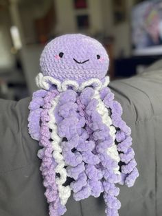 a purple and white crocheted octopus stuffed animal sitting on top of a couch