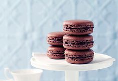 chocolate macaroons stacked on top of each other on a white cake platter