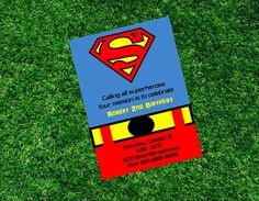 a birthday card with a superman logo on it sitting in the middle of some grass