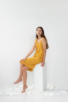 "Double gauze UMA sleeveless dress in mustard color. - length is ± 105 cm (41.3\") (depends on size) - with pockets - straight cut - loose fit NOTE: This dress is oversized, please have this in mind when choosing your size. DETAILS: - Oeko-Tex certified 100 % cotton (double gauze) - double gauze is naturally crinkly, and this will be even more noticeable after washing. - the model is 180 cm (5′11″) high, wearing size S. - model measurements: bust 84 cm (33\") / waist 61 cm (24\") / hips 92 cm (3 Sleeveless Linen Dress For Loungewear, Sleeveless Linen Loungewear Dress, Sleeveless Sundress Midi Loungewear, Sleeveless Sundress Midi Dress For Loungewear, Yellow Sleeveless Dress For Loungewear, Sleeveless Mustard Dress For Beach, Yellow Sleeveless Loungewear Dress, Casual Sleeveless Midi Sundress, Mustard Sleeveless Beach Dress