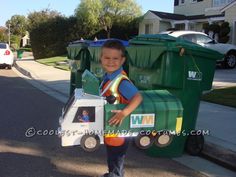 a young boy is standing in front of a garbage truck and holding a cardboard box