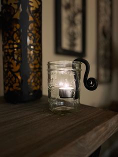 a glass jar sitting on top of a wooden table next to a vase with a candle in it