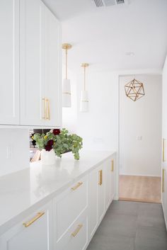 a kitchen with white cabinets and gold handles