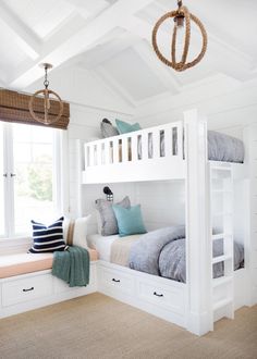 a white bunk bed sitting next to a window filled with pillows and throw pillows on top of it