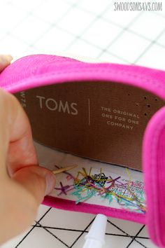 someone is painting the inside of a pink pair of shoes with crayon markers