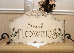 a wooden sign that says fresh flowers on the front and back of it, sitting on top of a bench