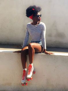 a woman sitting on top of a cement wall with roller skates around her ankles