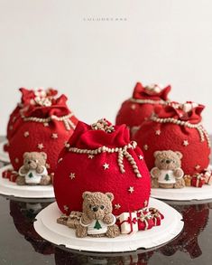 three small red bags with teddy bears in them on a black table top and white plate