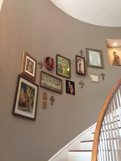 there are many framed pictures on the wall next to the stair case in this house