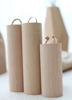 three wooden containers with rings on them sitting on a table next to a vase and lamp