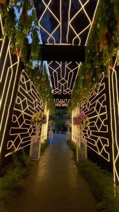 the walkway is lit up with lights and greenery