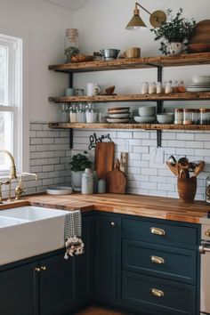 a kitchen with black cabinets and white subway backsplash, wood counter tops, gold pulls