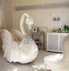 a white swan sculpture sitting in the middle of a living room next to a chair