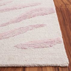 a pink and white rug on top of a wooden floor