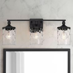 three light bathroom vanity fixture with clear glass jars on the front and back lights above it