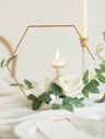 a candle and some flowers on a white bed with a hexagonal frame in the background