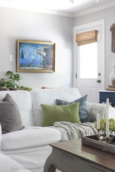 a living room filled with white furniture and lots of pillows on top of the couch