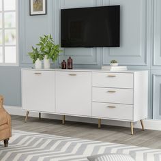 a living room with blue walls and a large tv on top of a white cabinet