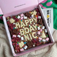 a pink box that says happy birthday with marshmallows and candies on it