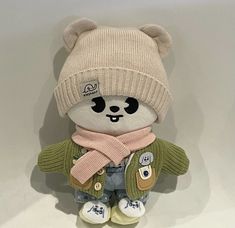 a teddy bear with a hat and scarf on it's head is sitting in front of a white wall