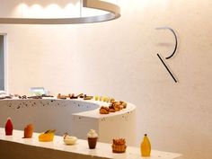 an assortment of desserts on display in a white room with circular light fixture hanging from the ceiling