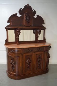 an ornate wooden cabinet with mirror on top