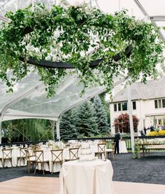 an outdoor dining area with tables, chairs and greenery hanging from the ceiling above