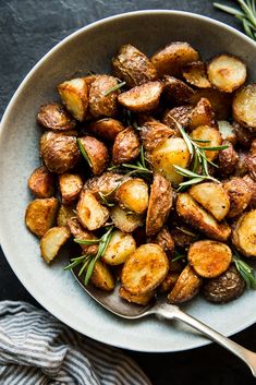 a white bowl filled with potatoes and rosemary