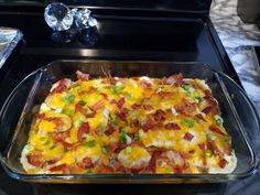 a casserole dish with bacon, cheese and green onions in it on a stove