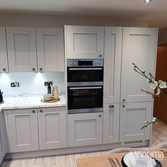 a kitchen with white cabinets and an oven in the center, along with a dining room table