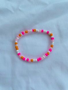 a pink and orange beaded bracelet on a white sheet