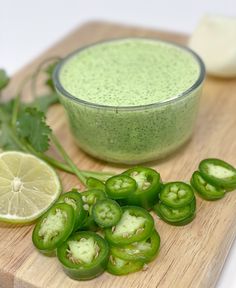 green vegetables on a cutting board next to a bowl of pesto sauce and limes