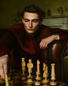 a man sitting at a chess board with his hand on the pawn's head